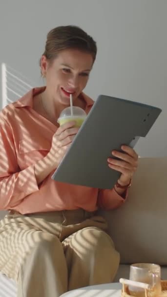 Вертикальный снимок деловой женщины средних лет, пьющей зеленый смузи и читающей бизнес-контракт - Кадры, видео