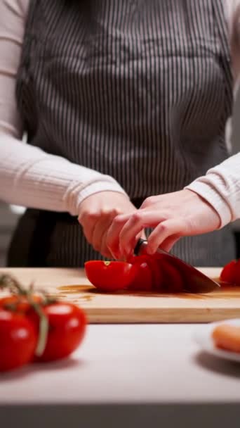 Χέρια νεαρών θηλυκών που κόβουν φρέσκια ντομάτα σε ξύλινη σανίδα ενώ ετοιμάζουν ιταλικά ζυμαρικά με λαχανικά και κιμά - Πλάνα, βίντεο