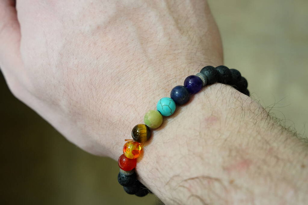 Bracelet en perles de chakra de roche de lave au poignet d'un homme - Photo, image