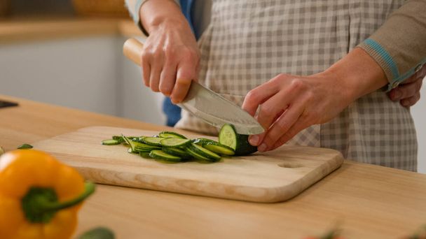 Сім'я дві кавказькі пари на кухні жінка готує овочевий салат, нарізаний свіжим чоловіком-огірком, обіймаючи приборкання прихильників ніжної любові до здорової їжі, готуючи їжу - Фото, зображення