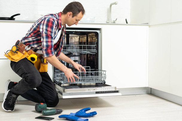 男性技術者は、デジタルマルチメータで食器洗い機を検査します.高品質の写真 - 写真・画像