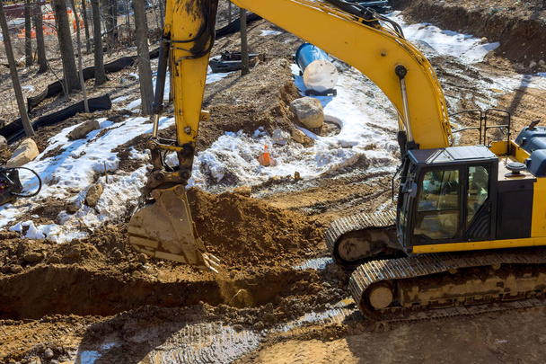 A nagy kotrógép földmunkát ás egy építkezés alatt álló ipari területen. - Fotó, kép