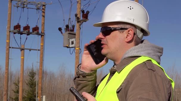 Электроинженер разговаривает по мобильному телефону на открытом воздухе
 - Кадры, видео