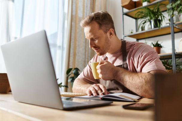 Egy férfi ül egy laptopnál egy gyárilag megtöltött munkahelyen, és a kis üzleteire koncentrál.. - Fotó, kép