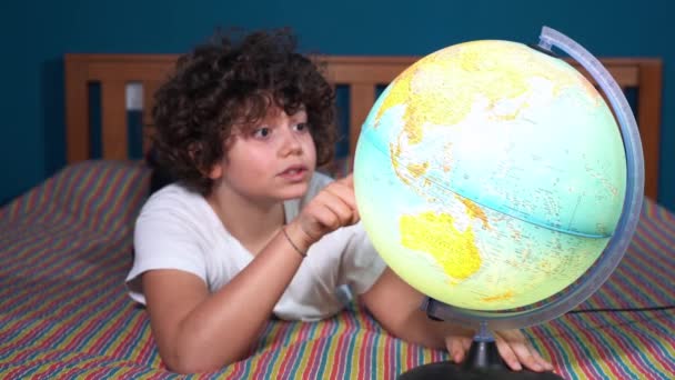 ragazzo che guarda il globo e sogna dove viaggiare nel futuro, lo stile di vita durante l'infanzia e il desiderio di viaggiare e scoprire il mondo - cambiamento climatico e concetto di riscaldamento globale - Filmati, video