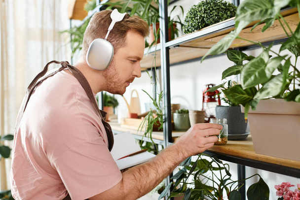 Ein Mann mit Kopfhörern blickt in einem Pflanzenladen auf eine Pflanze, die in perfekter Harmonie die Essenz von Natur und Musik verkörpert. - Foto, Bild