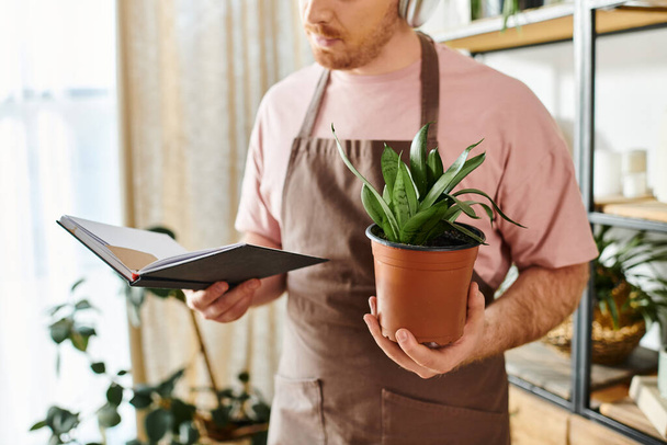Un hombre apuesto tiende a una planta en maceta en su floreciente tienda de plantas, encarnando la esencia de un dueño de una pequeña empresa. - Foto, Imagen