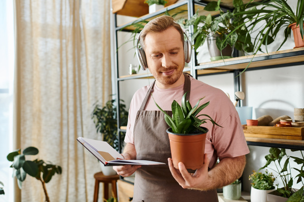 A man in an apron lovingly holds a potted plant, showcasing his passion for plants and nature. - Photo, Image