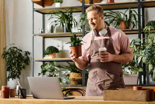 Un hombre en un delantal disfrutando de una taza de café en una tienda de plantas. - Foto, Imagen
