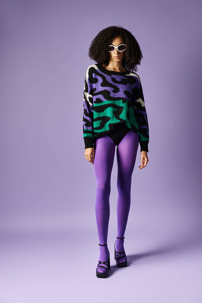 紫色と緑色のセーターでポーズを打つ若い女性と紫色のスタジオの背景に紫色のタイツ. - 写真・画像