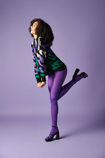 若い女性はスタジオの設定で紫色の背景に対してタイツと緑と黒のジャケットでポーズします. - 写真・画像