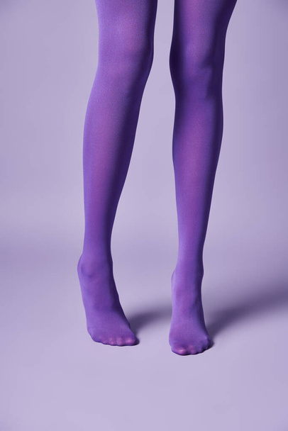 Une jeune femme en bas violets vibrants frappant une pose sur un fond violet dans un studio. - Photo, image