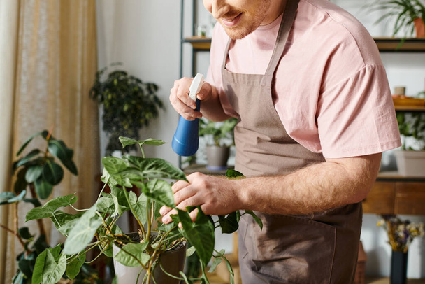 エプロンの男は慎重に植物工場で植物を散布し,庭園での彼の専門知識を紹介しています. - 写真・画像