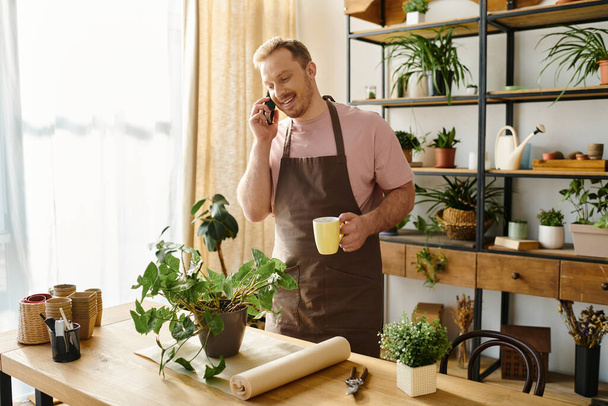 Мужчина стоит на кухне, разговаривает по мобильному телефону, многозадачен в среде малого бизнеса. - Фото, изображение