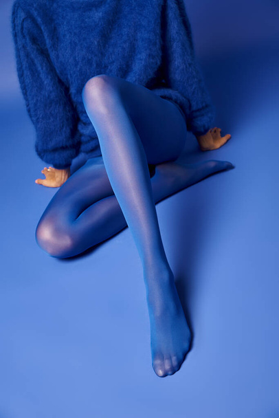 A young womans legs in vibrant blue stockings against a blue background, exuding grace and elegance. - Photo, Image