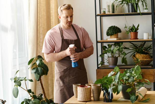 Un uomo tende a piante in vaso su un tavolo in un ambiente botanico. - Foto, immagini