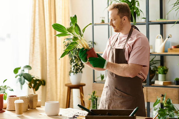 Un hombre en un delantal sostiene una planta verde en una bulliciosa tienda de plantas. - Foto, imagen