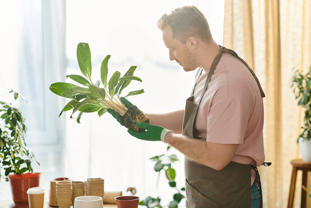 Красивый мужчина нежно держит в руках процветающее растение в своем собственном цехе, воплощая суть предпринимательства и заботы.. - Фото, изображение