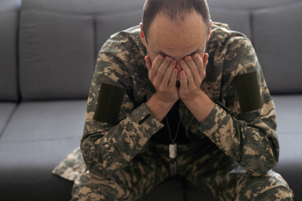 Conceito PTSD homem militar senta-se em um soldado de fundo preto sofre. Foto de alta qualidade - Foto, Imagem