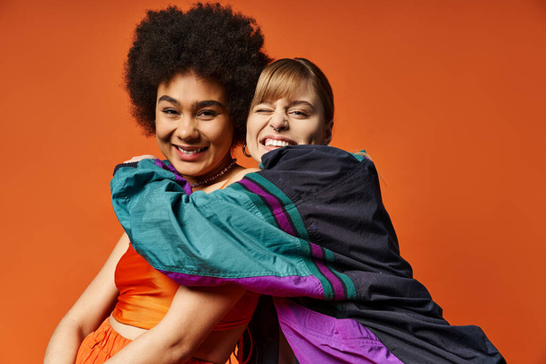 Dos mujeres de diferentes razas de pie juntas sobre un fondo naranja, abrazando la belleza de la primavera. - Foto, imagen