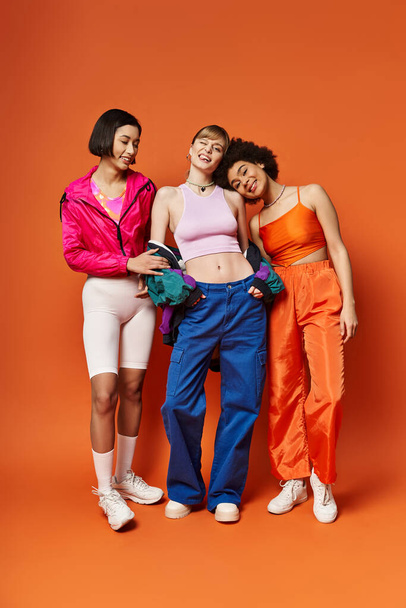 Eine Gruppe multikultureller junger Frauen, die vor orangefarbenem Hintergrund zusammenstehen und Schönheit und Einheit ausstrahlen. - Foto, Bild