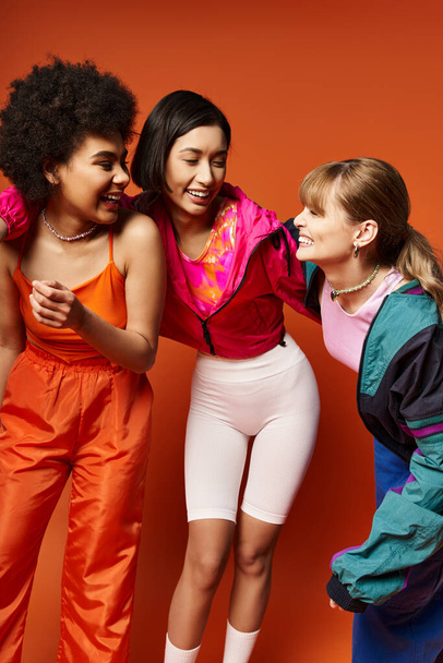 A group of young women of various ethnicities and backgrounds standing together in solidarity in a studio with an orange background. - Photo, Image