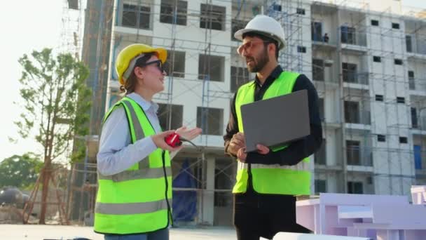 Team architect and builder talking and holding laptop looking model house at construction site, contractor and worker discussion and planning strategy about of real estate, engineer concept. - Footage, Video