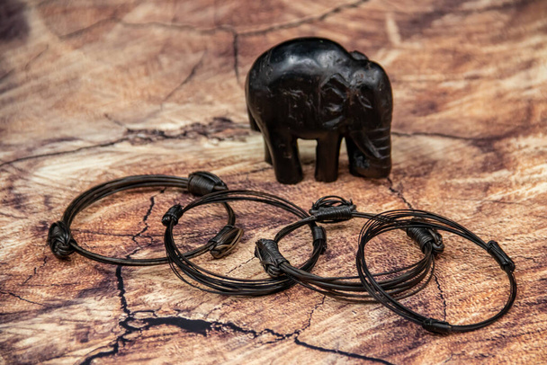 Pulseras africanas hechas de pelo de elefante de la cola, con pequeña figura de elefante en el fondo - Foto, imagen