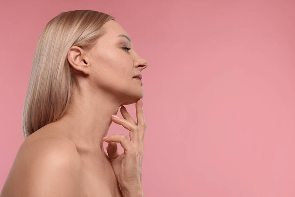 Beautiful woman touching her neck on pink background. Space for text - Fotoğraf, Görsel