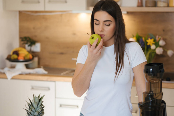 Mladá žena drží zelené jablko v ruce a čichá k němu. . Kvalitní fotografie - Fotografie, Obrázek