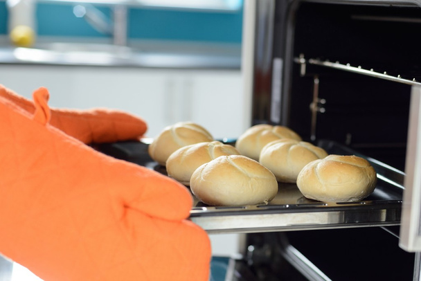Τα χέρια βάζοντας στο φούρνο ψωμί ρολά - Φωτογραφία, εικόνα