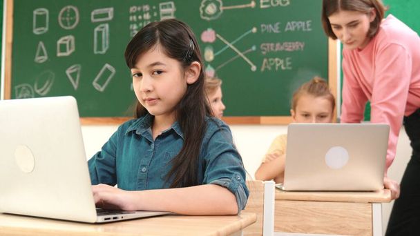 Smart asian girl looking at camera while coding engineering prompt. Multicultural student learning about generated AI while teacher teaching about system or checking classwork at STEM class. Pedagogy. - Fotó, kép