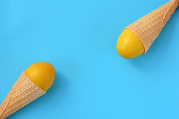 huevos amarillos en conos de gofre sobre fondo azul claro - Foto, imagen
