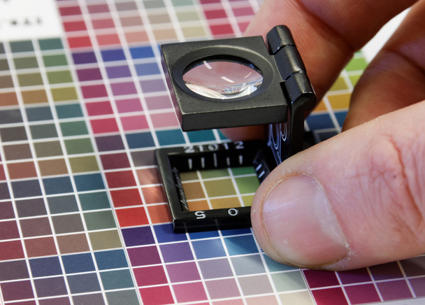 Primer plano de una lupa en un colorido estampado de prueba
 - Foto, Imagen