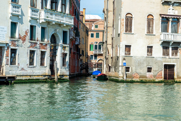 Venetsia, Veneto - Italia - 06-10-2021: Venetsian rauhallinen kanava, jota reunustavat sään ympäröimät rakennukset ja ankkuroidut veneet, jotka kuvaavat kaupungin ainutlaatuista charmia - Valokuva, kuva