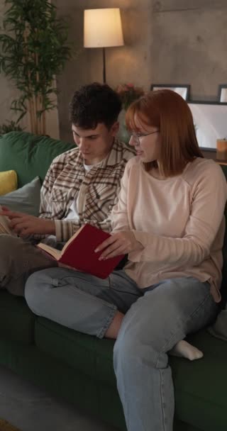 男と女性の慎重な大人のカップルはソファーベッドの自宅で本を読む - 映像、動画