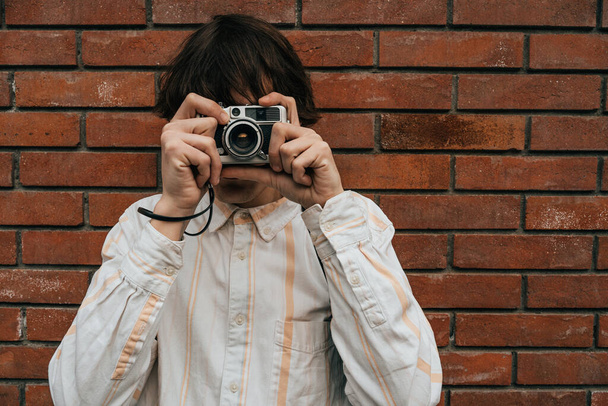 Enthousiaste photographe masculin cadrage tourné avec son vieil appareil photo vintage classique en ville. - Photo, image
