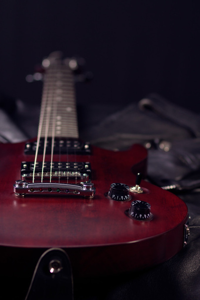 Ηλεκτρική κιθάρα που βρίσκονται στο μαύρο δερμάτινο μπουφάν - Φωτογραφία, εικόνα