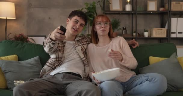 Pareja caucásico hombre y mujer sentarse en casa en sofá cama ver la película de televisión - Metraje, vídeo