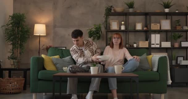 Ζευγάρι καυκάσιος άνδρας και γυναίκα κάθονται στο σπίτι στον καναπέ-κρεβάτι παρακολουθήσετε τηλεόραση ταινία - Πλάνα, βίντεο