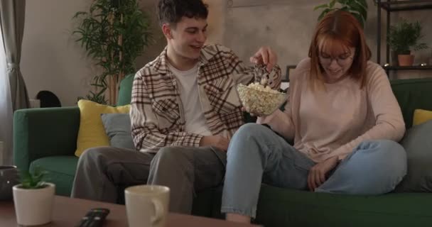 Paar Kaukasische man en vrouw zitten thuis op een slaapbank tv-film kijken - Video