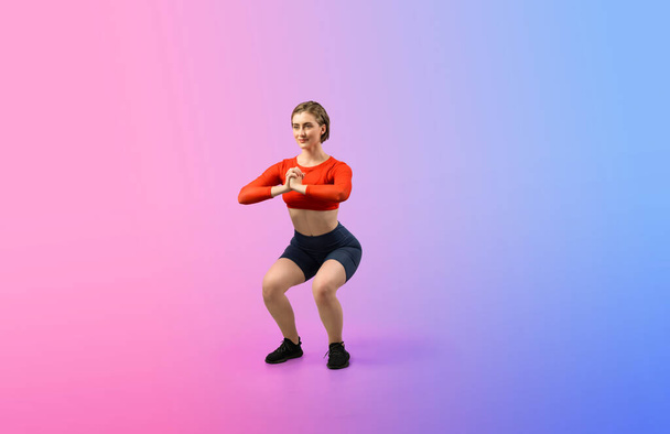 Gaieté pleine longueur du corps tourné athlétique et sportive jeune femme avec remise en forme en posture d'exercice squat sur fond isolé. Mode de vie sain et actif. - Photo, image