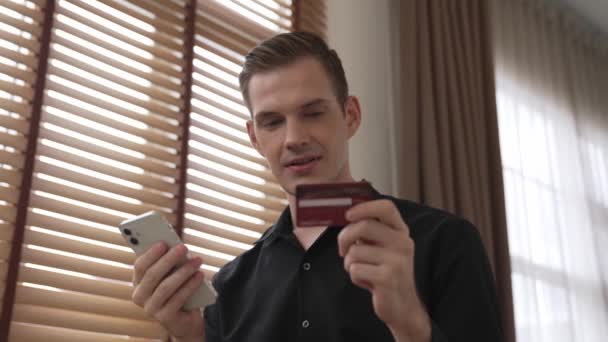 Junger Mann sitzt mit Online-Bezahl-App und digitaler Brieftasche am Smartphone am Tisch, um mit Kreditkarte zu bezahlen. E-Commerce-Einkauf und moderner Einkauf über das mobile Internet. Stollen - Filmmaterial, Video