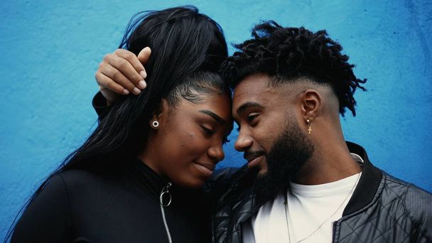 Genç Afro-Amerikan erkek ve kız kardeşler gerçek etkileşime önem veriyorlar. Alınları birbirine yaslanmış dışarıda mavi şehir duvarında duruyorlar. 20 'li yaşlardaki kardeşler birbirini sever. - Fotoğraf, Görsel