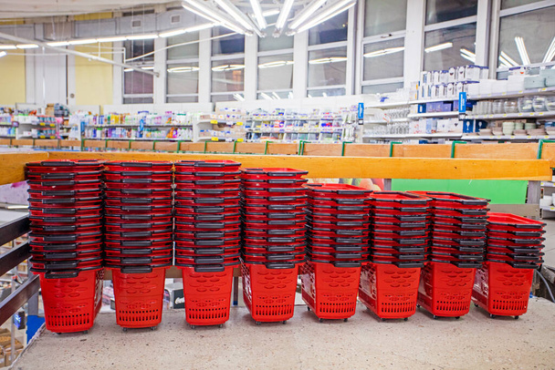 Rote Einkaufswagen für Lebensmittel und andere Waren stapeln sich in einem Supermarkt - Foto, Bild