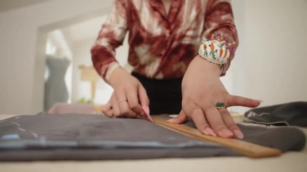 Abgeschnittene Aufnahme von Händen einer unkenntlichen Frau, die während ihrer Arbeit in der Näherei ein Stück Stoff mit Kreide markiert - Filmmaterial, Video