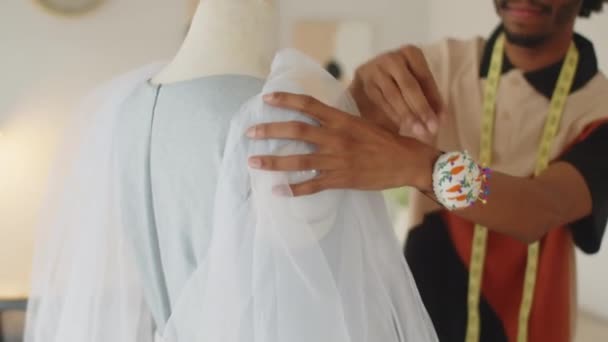 Focus op handen van mannelijke kleermaker bevestiging mouwen op trouwjurk werken in de studio - Video