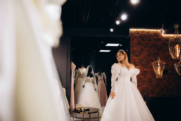 A beautiful bride is trying on a wedding dress in a store - Photo, Image