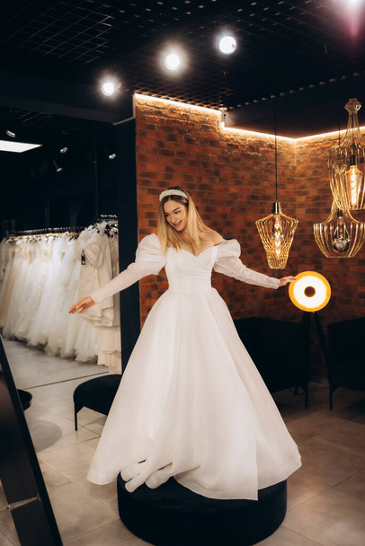 Bella sposa indossa un abito da sposa in un salone di nozze - Foto, immagini