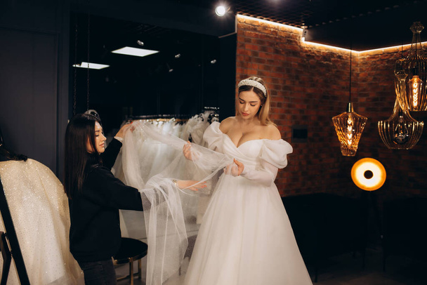 Junge Frau wählt Hochzeitskleid im Salon. Hochwertiges Foto - Foto, Bild